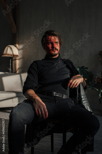 a tired man with a broken face covered in blood sits by the window. guy with makeup, cosplay