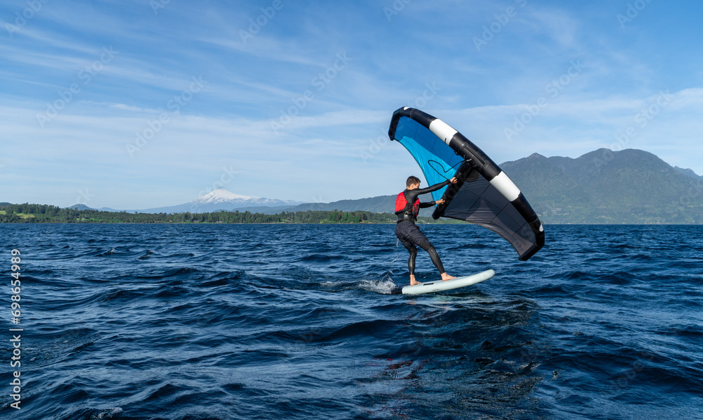 Young person learning to wingfoil on the lake with the volcano in the background.