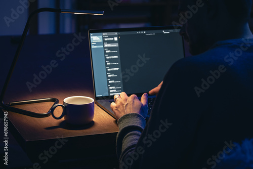 Dedicated businessman working late at laptop in dark office.