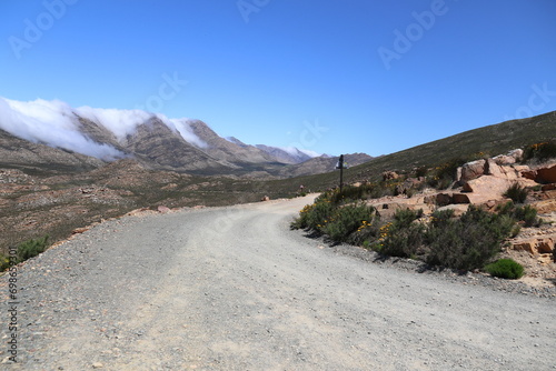 swartberg pass gravel road with clouds creeping over the mountains in the background photo