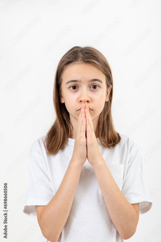 Teenager girl holds her hands in prayer on a white background isolated. Teenager girl holds her hands in prayer on a white background isolated.