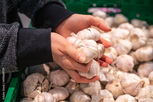A woman chooses garlic at a grocery store.