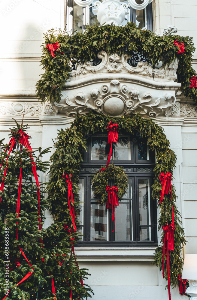 christmas decoration on the facade of a main building with red and green tree leaves and candies and bowties