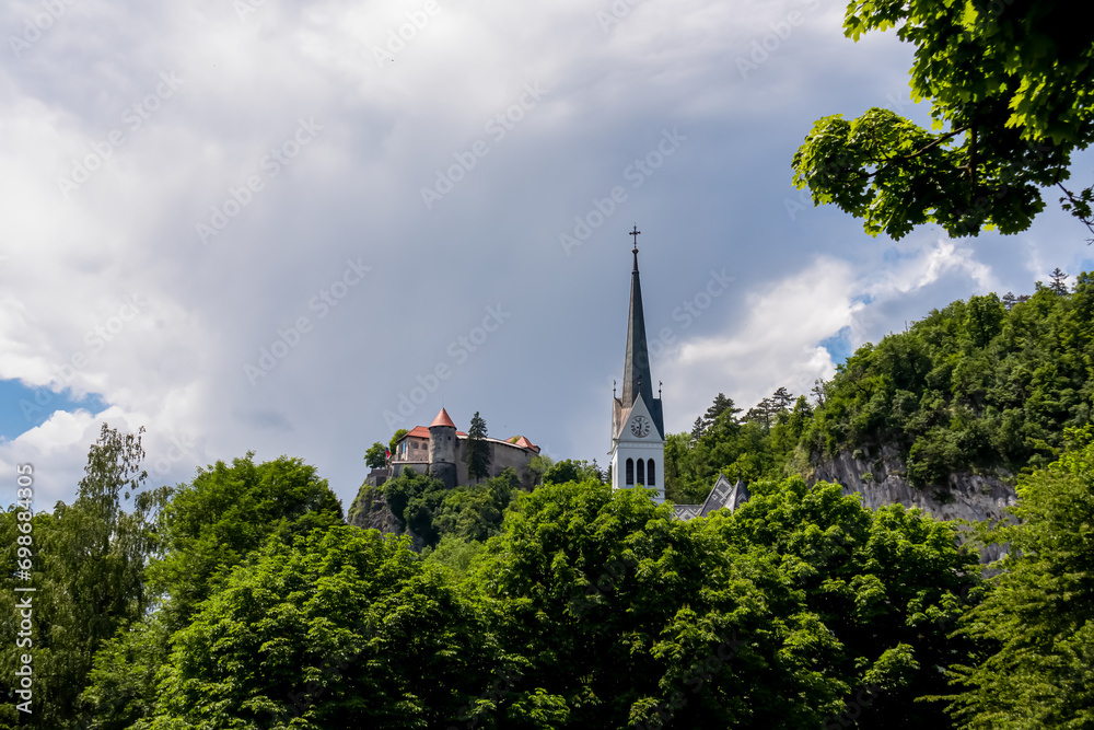 Panoramic view of St. Martina Parish Church and medieval castle at Lake Bled, Upper Carniola, Slovenia. Serene landscape in remote untouched nature in the Julian Alps in summer. Tourist attraction