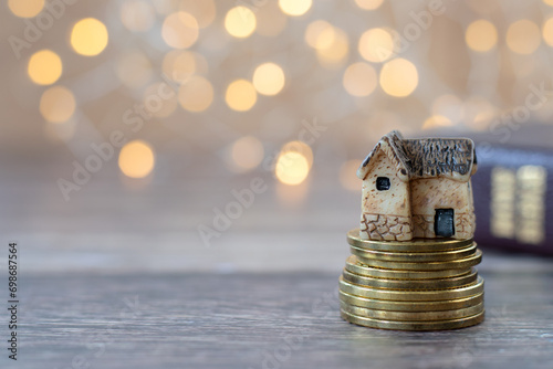 Miniature house and golden coins on wooden table and closed holy bible with bokeh background. Copy space. Selective focus. Christian tithe, finance, offering,  home blessing concept.
