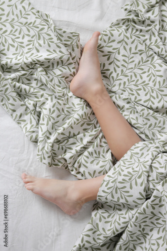 Fotografie Child feet under cotton bedcover under soft morning light