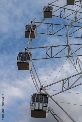 The Ferris wheel attraction is large against the backdrop of a cloudy, textured sky. Vertical photo