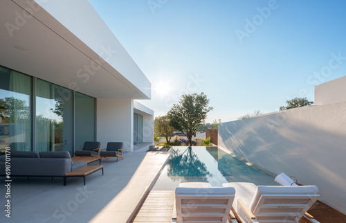 Modern minimalist sustainable house with a clear blue pool with sleek white walls, and a serene sky backdrop