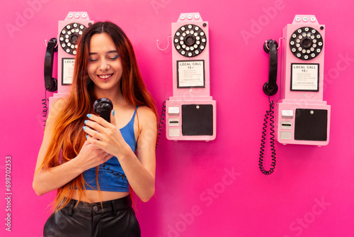 Smiling Young Woman Holding Pink Phone on Pink Background photo