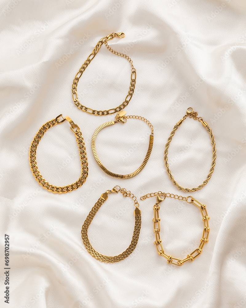 Set of gold chain bracelets on cream silk fabric