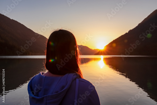 Woman enjoying allure of sunset at alpine lake Weissensee in remote Austrian Alps in Carinthia. Embrace serene ambiance as tranquil surface of water amplifies sun gentle rays. Sun gracefully descends photo