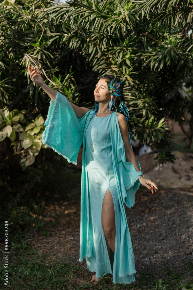 Beautiful young woman in long turquoise dress performs ceremony of meeting sun. Unity with nature. 