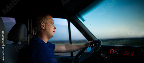 young male truck driver driving a truck during the day. work as a driver
