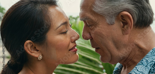 an older old cauasian man with gray hair, on tropical vacation or emigrated, with younger asian or thai girlfriend or wife, kissing, intercultural love, being in love, affection and vacation flirt photo