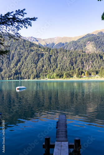 Scenic view of Latschur mountain peak from enchanting wooden pier at alpine lake Weissensee in Gailtal Alps, Carinthia, Austria. Lakeside Retreat in serene landscape amidst untouched nature in summer photo