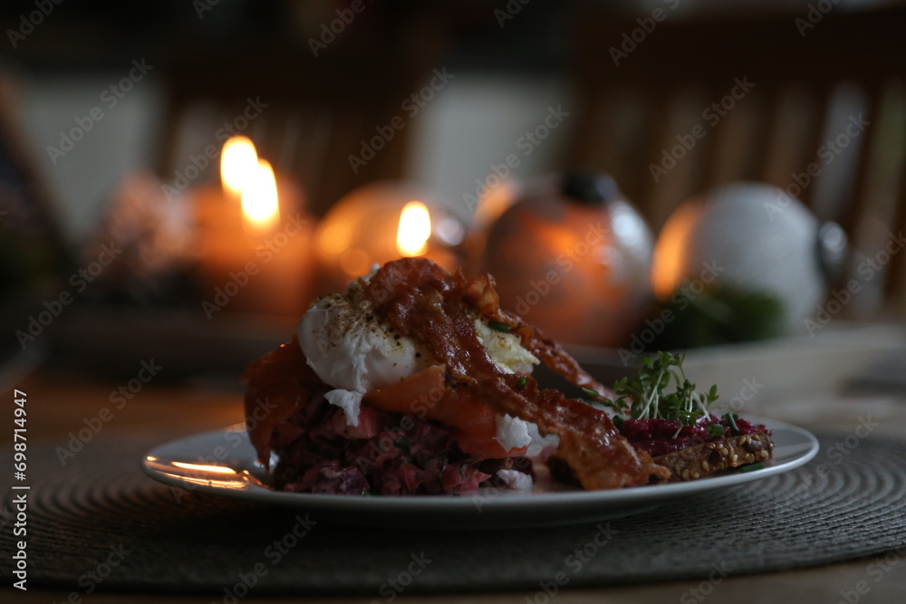 Breakfast arrangement with salmon tartar, poached egg and fried bacon in living room