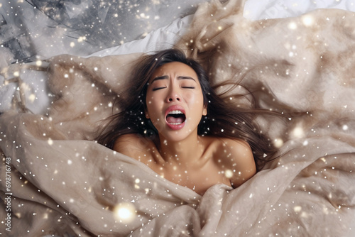 Young asian woman having orgasm. Woman with open mouth and closed eyes enjoying sex lying among flying glitter and sparkles as a symbol of orgasm. Sexual experience, masturbation, cunnilingus. photo