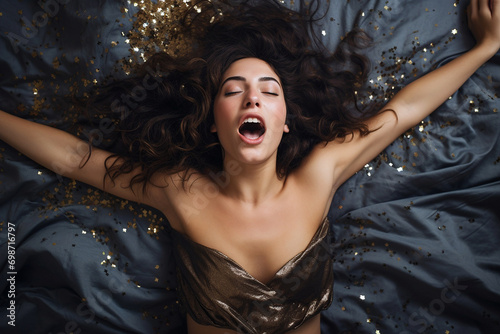 Young european woman having orgasm. Woman with open mouth and closed eyes enjoying sex lying among flying glitter and sparkles as a symbol of orgasm. Sexual experience, masturbation, cunnilingus. photo