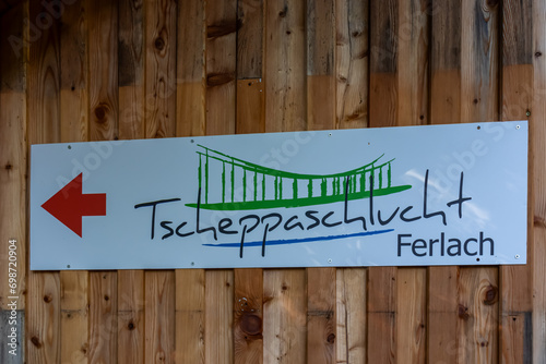 Information sign showing the direction to the Tscheppaschluch gorge near Ferlach in Carinhtia, Austria. The sign is mounted on a wooden wall photo