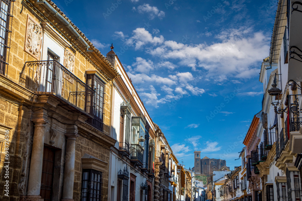 Spectacular and historic Seville street in Osuna, Seville, Andalusia, Spain, with the collegiate church in the background on a hill - obrazy, fototapety, plakaty 