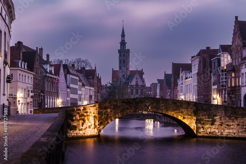 Twilight settles over the tranquil canals and medieval buildings of Brugge, Belgium, with a stone bridge in the foreground photo