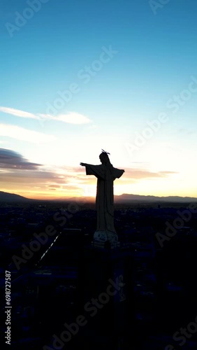 Traveling out de Silhouette of a giant statue of Jesus Christ with the blue evening sky in the background. Vertical drone video. Christ of Monteagudo, Murcia. photo
