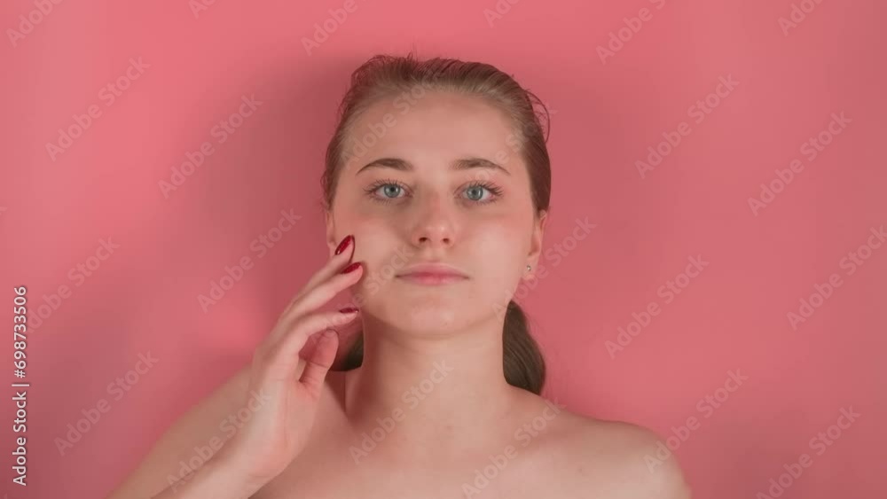 The pink background shows a young, attractive girl without makeup. She is lying ostensibly underwater stroking her face with a manicured hand and looking into the camera. While the water makes waves The pink background shows a young, attractive girl without makeup. She is lying ostensibly underwater stroking her face with a manicured hand and looking into the camera. While the water makes waves