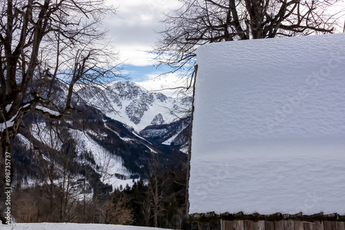 Small chapel with panoramic view on Baerental valley in Austrian Alps. Snow capped mountain peaks of Karawanks and Julian Alps in Carinthia, Austria. Looking at summits Kosiak and Hochstuhl. Serenity photo