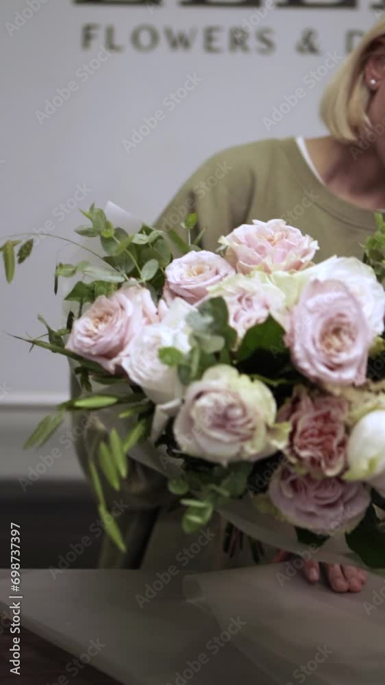 Florist makes bouquet in flower shop Vertical Elya Florist makes bouquet in flower shop Vertical Elya