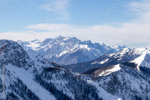 Panoramic view on snow capped mountain peaks of Karawanks and Julian Alps in Carinthia, Austria. Looking at summits Mangart and Montasio. Remote alpine landscape in Baerental. Mystical cloudy sky © Chris