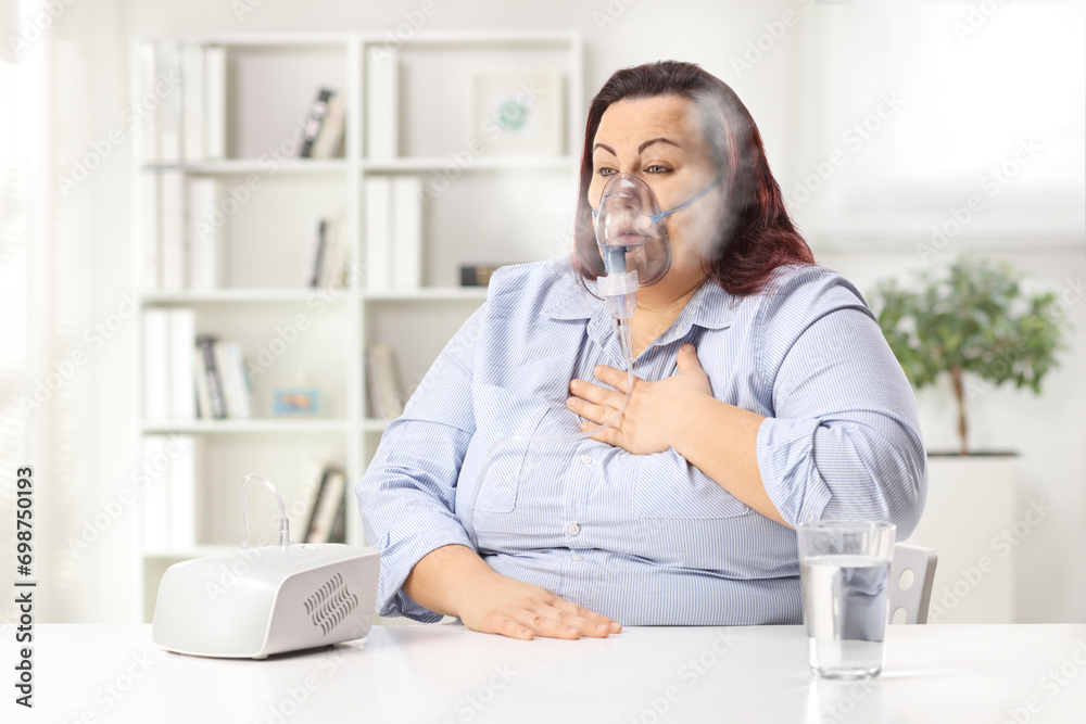 Woman holding her chest and using a nebulizer with vapor mist