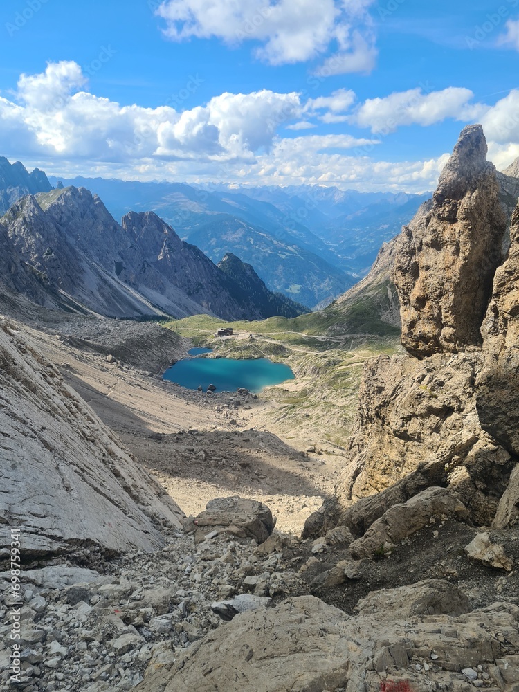Valley with the small lake Laserz in the middle, located between sharp and stony mountain range of Lienz Dolomites, Austria. The slopes are barren, with little grass on it. Dangerous climbing.