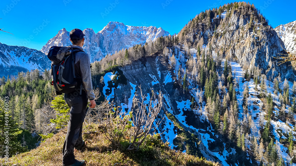 Hiker man enjoying scenic view of Karawanks mountain range in Carinthia, Austria. Looking at snow capped summit of Vertatscha and Hochstuhl. Remote alpine landscape in Bodental, Austrian Alps