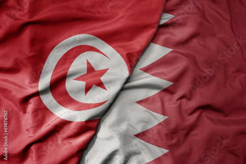 big waving national colorful flag of bahrain and national flag of tunisia .
