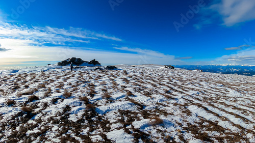 Woman with hiking backpack walking on snow covered alpine meadow on trail from Ladinger Spitz to Geierkogel, Saualpe, Lavanttal Alps, Carinthia, Austria. Snow capped mountain ranges of Austrian Alps photo