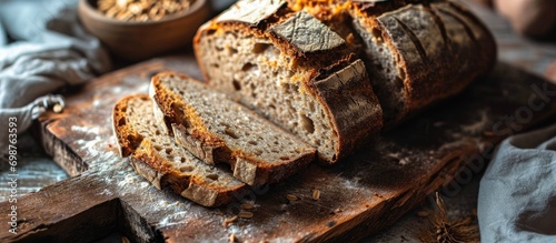 Sliced homemade spelt and wheat bread with rustic crust and open crumb texture on wooden board.