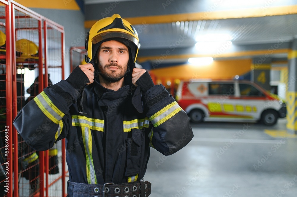 Fototapeta premium Fireman wearing protective uniform standing in fire department at fire station