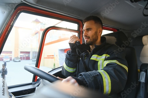 Firefighter using radio set while driving fire truck photo