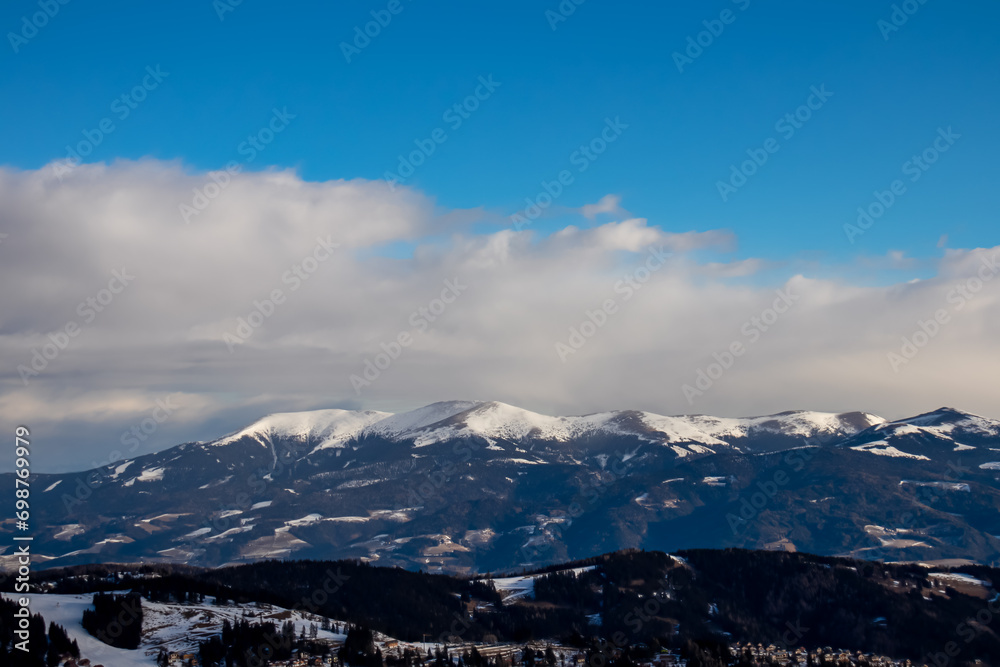 Panoramic view of snow capped mountain peaks and hills of Packalpe, Carinthia Styria border, Austria, Europe. Alpine hiking trail in Central Austrian Alps in winter wonderland. Snowy landscape