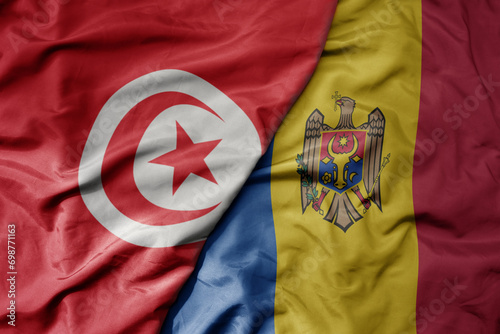big waving national colorful flag of moldova and national flag of tunisia .