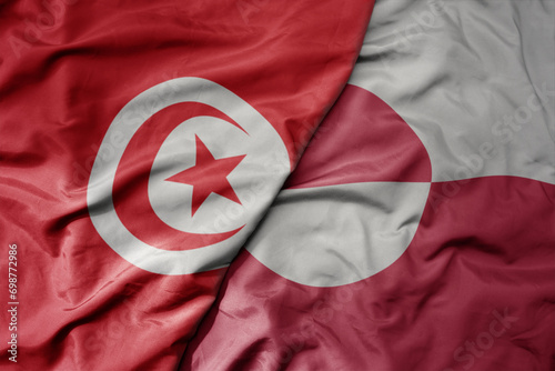 big waving national colorful flag of greenland and national flag of tunisia .