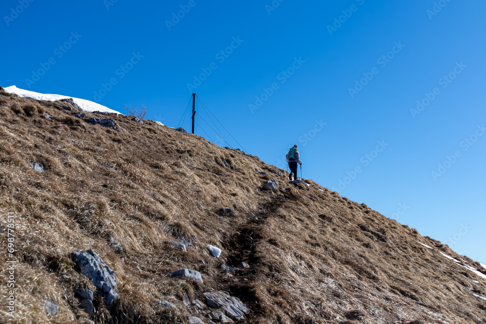 Woman on panoramic hiking trail on way to snow covered mountain peak Ferlacher Horn in Carinthia, Austria. Alpine landscape of Austrian Alps. Wanderlust in tranquil serene nature. Winter wonderland