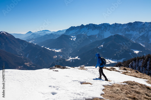 Man on panoramic hiking trail on way to snow covered mountain peak Ferlacher Horn in Carinthia, Austria. Alpine landscape of Austrian Alps. Wanderlust in tranquil serene nature. Winter wonderland