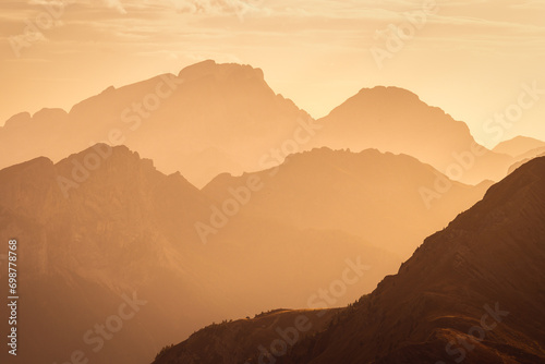 Obraz na płótnie Italian Dolomites in colorful golden sunrise. Misty Alpine mountains in haze. Silhouettes of mountain peaks. w salonie
