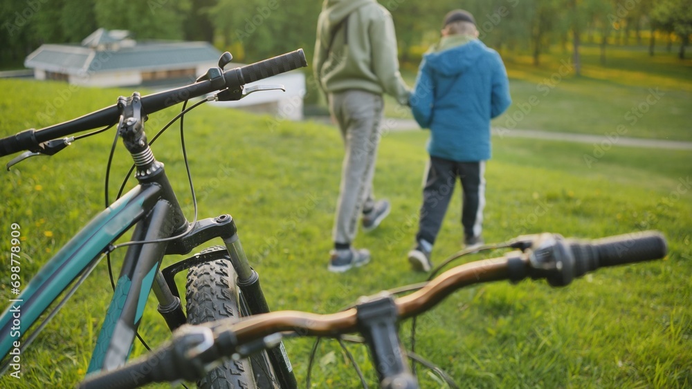 Two boys relaxing in the park in front of their bicycles. Two boys relaxing in the park in front of their bicycles.