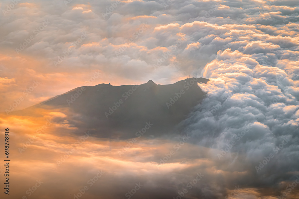 Italian Dolomites in colorful golden sunrise. Misty Alpine mountains in haze. Silhouettes of mountain peaks.