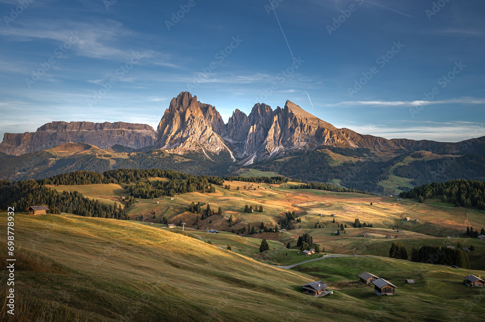 Stunning sunset at Langkofel with colorful sky at Italian Dolomites. Impressive Sassolungo mountain with Alpine lodges.