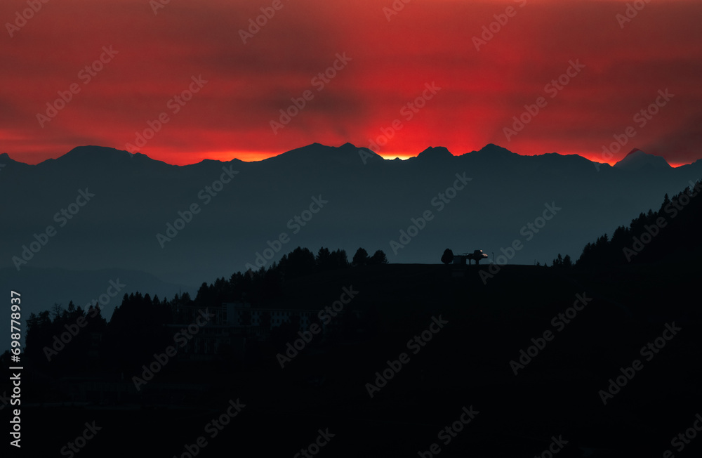 Dark red sky at Italian Dolomites with mountain peaks in distance. Twillight hour at Italian Alps.