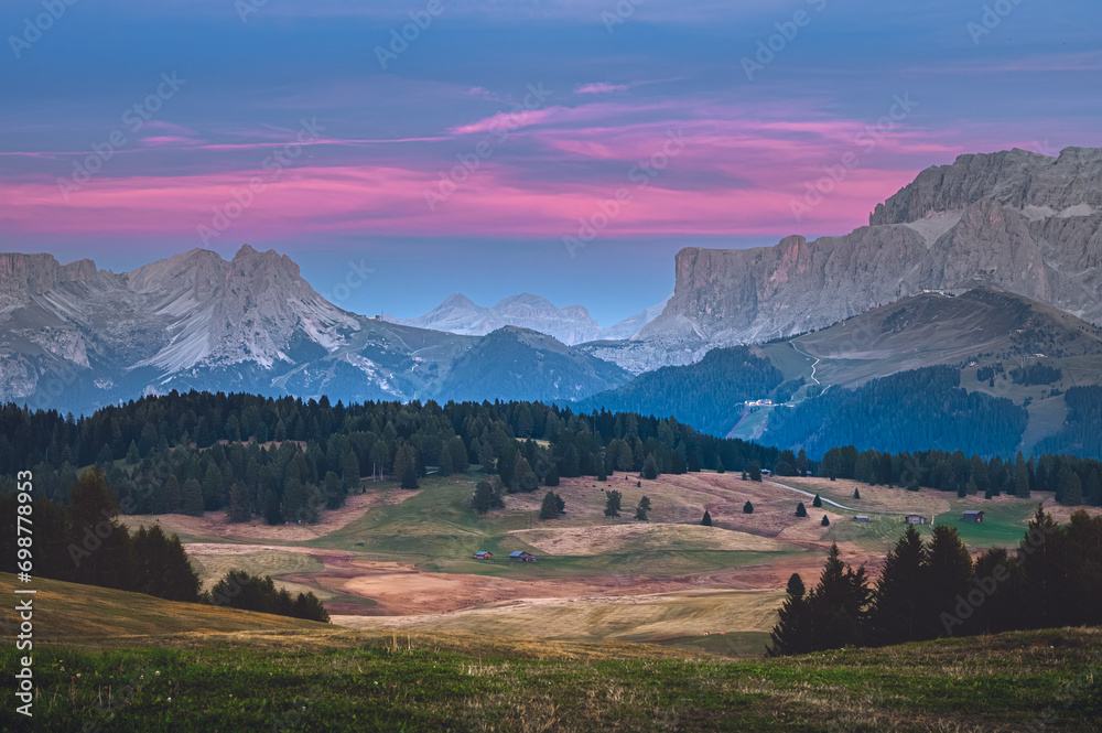 Stunning sunset at Langkofel with colorful sky at Italian Dolomites. Impressive Sassolungo mountain with Alpine lodges.