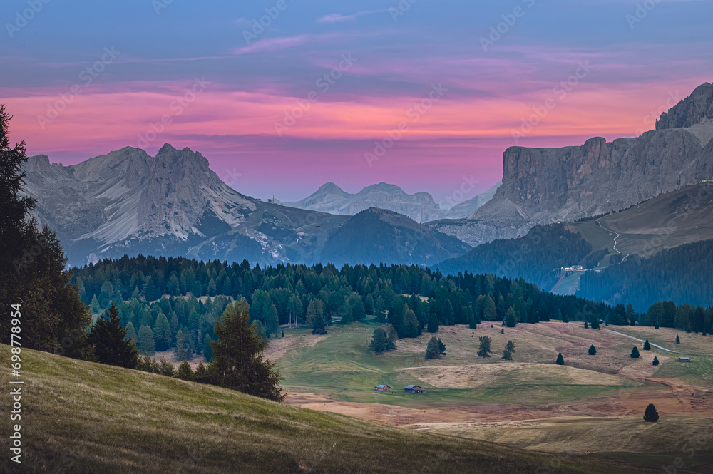 Stunning sunset at Langkofel with colorful sky at Italian Dolomites. Impressive Sassolungo mountain with Alpine lodges.